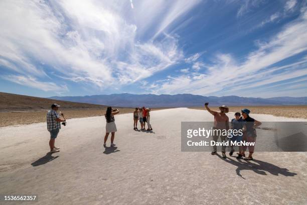 People walk on the salt flat at Badwater, the lowest point in North America at 282 ft below sea level, as the temperature rises well into the upper...