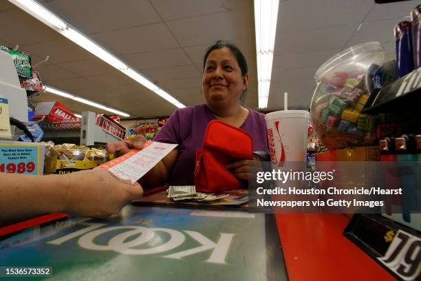 Eva Armendariz buys a Lotto ticket from Khen Lee, owner of the Stop at Joe's Food Store at 6412 Main. Lotto has reached $72 million. Photo by Steve...