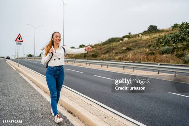 junge frau trampt auf einer autobahn in malta - malta wandern stock-fotos und bilder