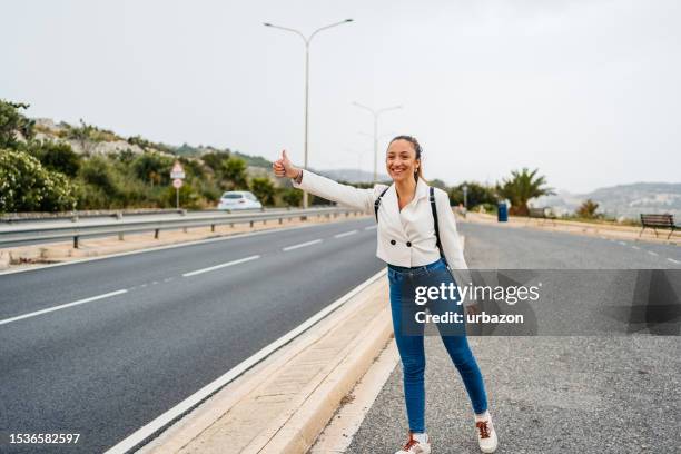 junge frau trampt auf einer autobahn in malta - malta wandern stock-fotos und bilder