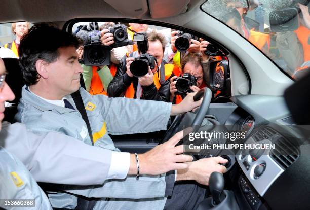 French Minister for Industrial Renewal Arnaud Montebourg sits in a Renault ZE electric car as he visits the plant of the French carmaker on October...