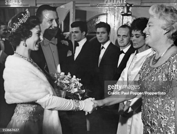 Queen Elizabeth II shakes hands with English singer Gracie Fields at the Royal Variety Performance at the London Palladium, 2nd November 1964. Left...