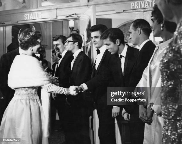 Queen Elizabeth II shakes hands with singer Cliff Richard at the Royal Variety Performance at the London Palladium, 2nd November 1964. Left to right:...