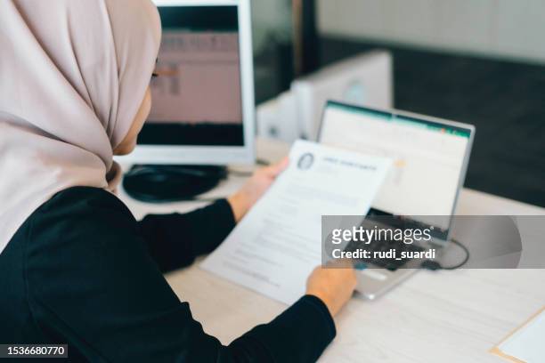business muslim woman reading a resume on paper to hire correct personnel - job vacancy stock pictures, royalty-free photos & images