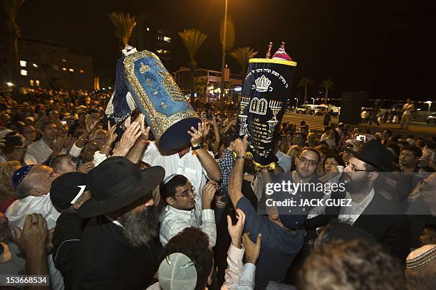 Jews dance with Torah scrolls during the Simhat Torah celebration in the Mediterranean coastal city of Netanya, north of Tel Aviv, on October 8,...