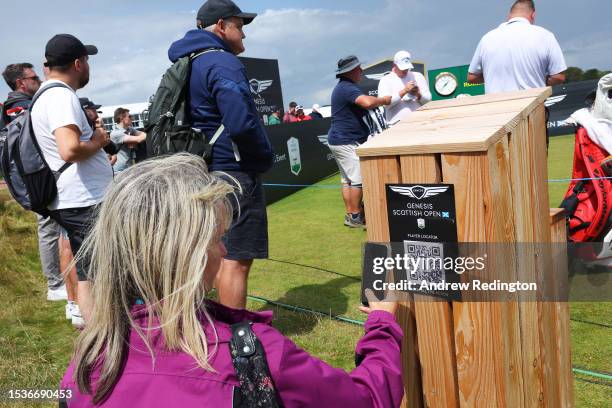 Fan scans a QR code sign for a player locator map prior to the Genesis Scottish Open at The Renaissance Club on July 12, 2023 in United Kingdom.