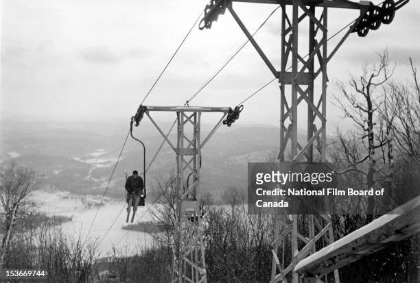 High angle view of a skier riding a chairlift up the slopes with the Laurentian mountains in the background, Sainte-Agathe-des-Monts, the...