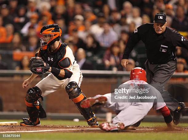 Joey Votto of the Cincinnati Reds slides home past Buster Posey of the San Francisco Giants during Game 2 of the NLDS at AT&T Park on Sunday, October...