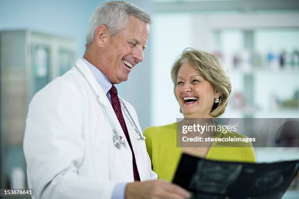 doctor showing x-ray image to cheerful mature female patient. - 70 x 54 stock pictures, royalty-free photos & images