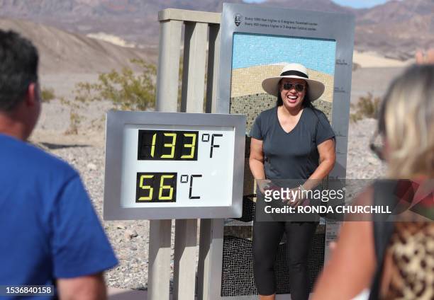 Melanie Anguay, of Las Vegas, stands for a photo next to a digital display of an unofficial heat reading at Furnace Creek Visitor Center during a...