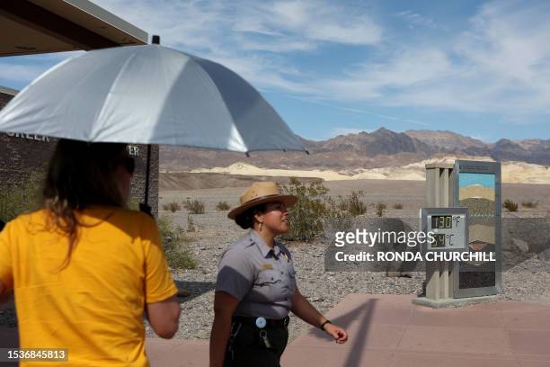 National Park Service Ranger Gia Ponce walks near a digital display of an unofficial heat reading at Furnace Creek Visitor Center during a heat wave...