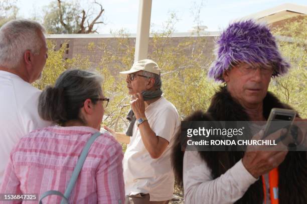 Tourists stand in the shade outside Furnace Creek Visitor Center during a heat wave in Death Valley National Park in Death Valley, California, on...
