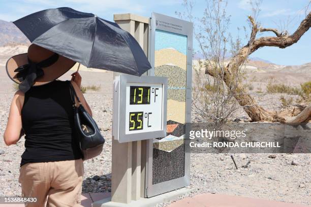 Woman stands near a digital display of an unofficial heat reading at Furnace Creek Visitor Center during a heat wave in Death Valley National Park in...