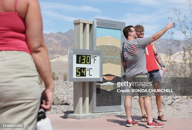 Jim Brigance of Atlanta, takes a photo with son Will as they stand next to a digital display of an unofficial heat reading at Furnace Creek Visitor...