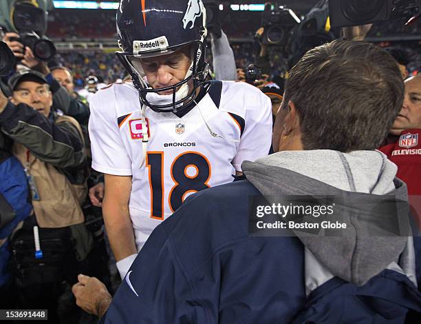 Broncos quarterback Peyton Manning wears a glum look as he shakes hands with Patriots head coach Bill Belichick, right, following New England's 31-21...