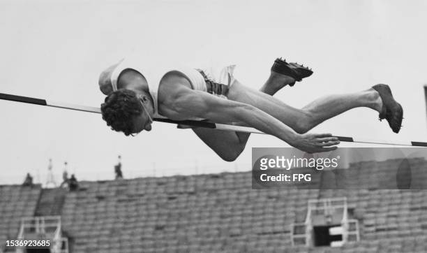 American athlete Irving Mondschein clears the bar during the high jump event at the Intercollegiate Association of Amateur Athletes of America...