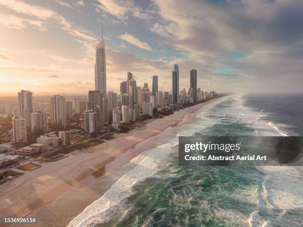 aerial image at sunset showing city skyscrapers and waves from the coral sea washing onto surfers paradise beach, gold coast, queensland, australia - gold coast skyline stock-fotos und bilder