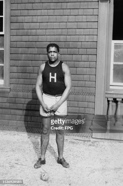 American athlete Ted Cable, wearing a Harvard University singlet and white shorts, posing with a hammer throw 'hammer', United States, circa 1913....