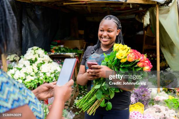 mujer se prepara para hacer pago sin contacto por flores - vendedor del mercado fotografías e imágenes de stock