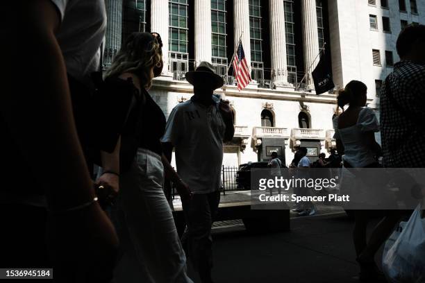 People walk past the New York Stock Exchange on July 12, 2023 in New York City. New government data released Wednesday showed that inflation fell to...