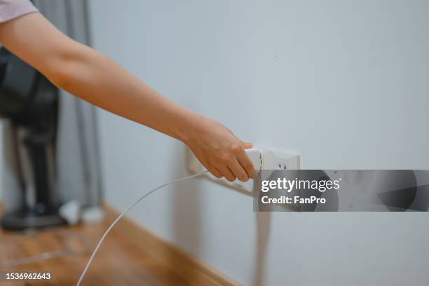 a girl is plugging in a plug to charge a mobile phone - enchufar fotografías e imágenes de stock
