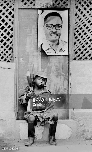 Young soldier of the Popular Movement for the Liberation of Angola is seated on a doorstep 23 February 1976 in Huambo. Over his heads hangs the...