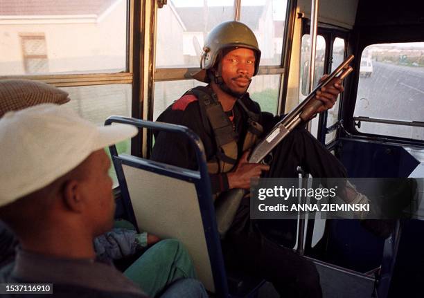 An armed private security guard rides shotgun aboard a Golden Arrow bus in Khayelitsha, Cape Town, 28 June 2000. Golden Arrow hired a security...