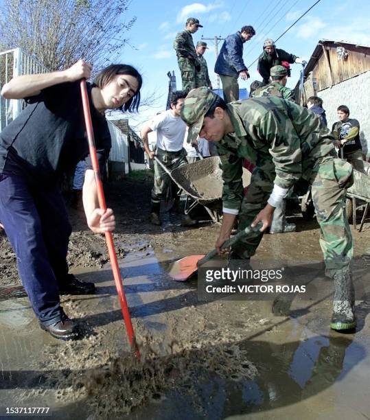 Chilean soldiers try to clear mud and rubbish from a flooded street in Santiago 15 June, 2000. Miembros del ejercito chileno cooperan en retirar...