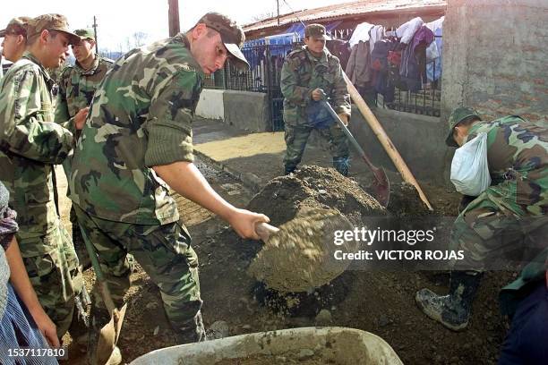 Chilean soldiers try to clear mud and rubbish from a flooded street in Santiago 15 June, 2000. Miembros del ejercito chileno cooperan en retirar...
