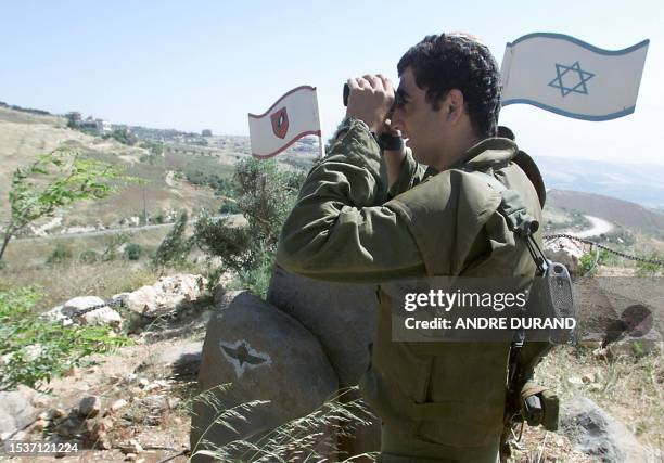 An Israeli army soldier peers through binoculars at the Lebanese village of Kfar Kila 27 May 2000 from Misgav-Am on the border between the two...