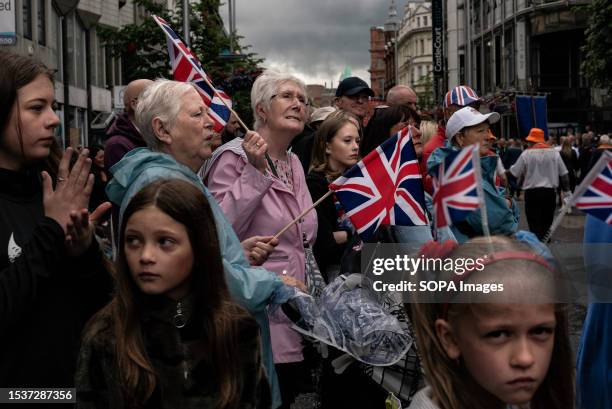 Group of spectators holding union jacks flags watch the Orange march. Protestants marched through the streets of Belfast on Twelfth of July parades...