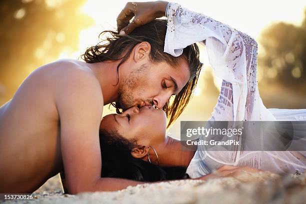 young couple kissing at sunset - black women kissing white men stock pictures, royalty-free photos & images