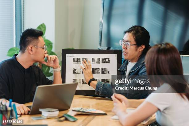 asian chinese handsome young adult giving presentation with team at design studio - storyboard stock pictures, royalty-free photos & images