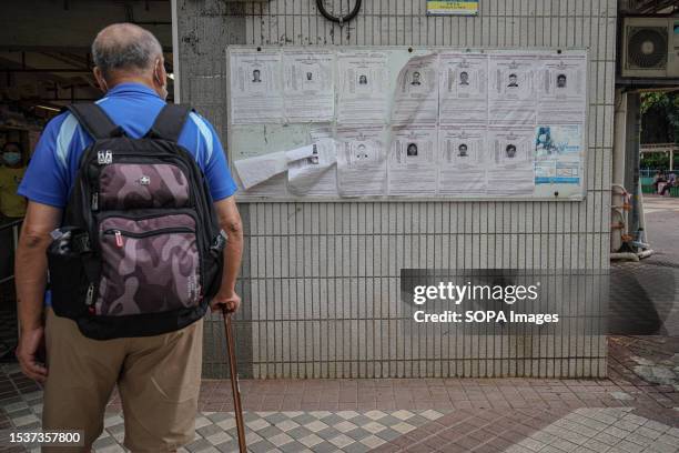 Man looks at the profiles of wanted political activities on a noticeboard in Wah Fu Estate. Hong Kong police force wanted eight Hong Kong political...