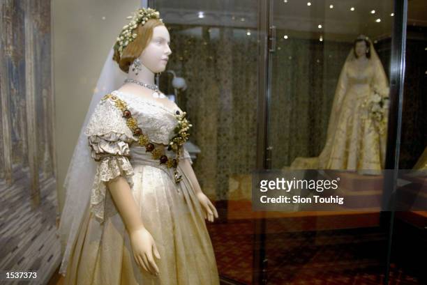 Mannequin of Britain's Queen Victoria, wearing her wedding dress, stands in front of a model of Queen Elizabeth April 30, 2002 at the launch of the...