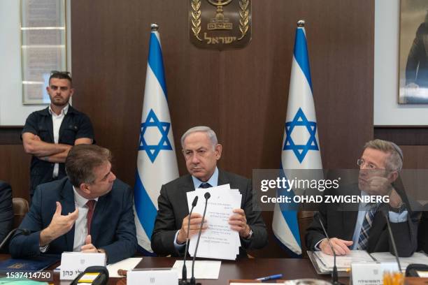 Israel's Prime Minister Benjamin Netanyahu listens to Foreign Minister Eli Cohen , as cabinet secretary Yossi Fuchs looks on during a weekly cabinet...