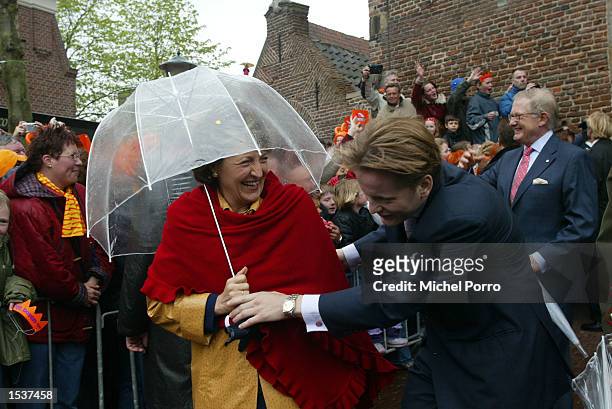 Dutch Prince Pieter Christiaan ducks under the umbrella of his mother, Princess Margriet, the sister of Queen Beatrix, during the celebrations for...