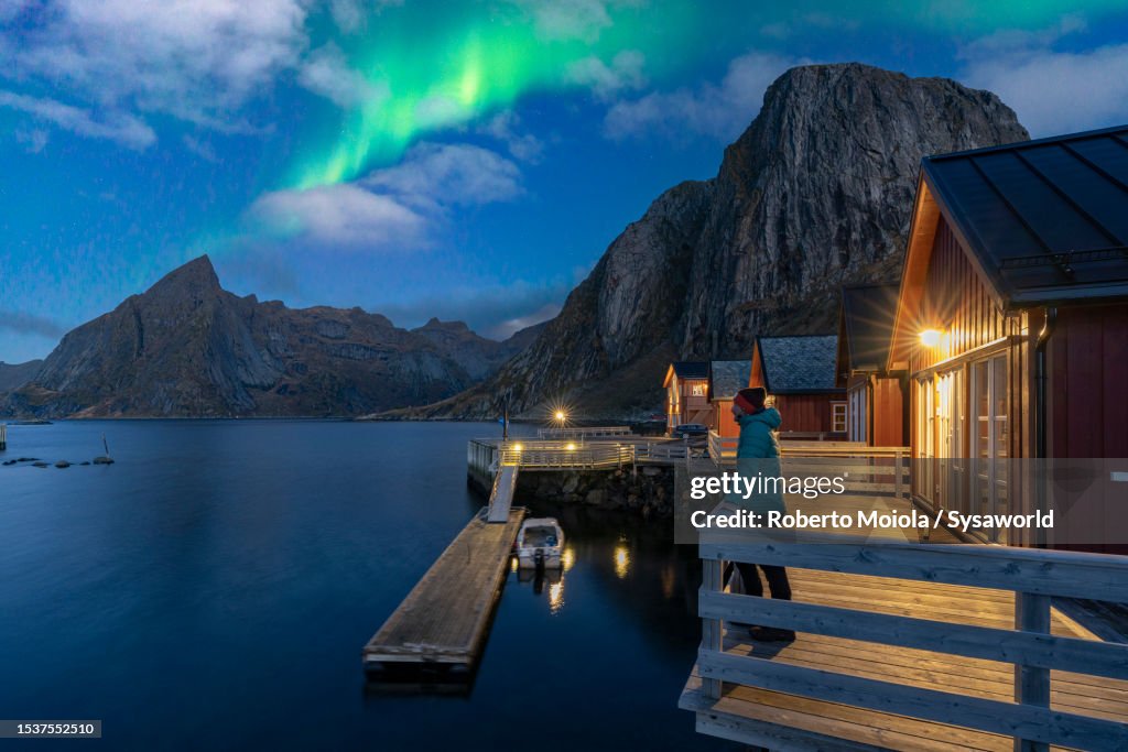 Hiker admiring the Northern Lights standing on pier