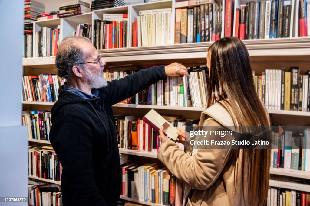 Funcionário ajudando aluno a encontrar um livro na biblioteca