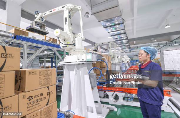 Industrial robots work on a wipes packaging line at the smart factory of a cosmetics company in Huzhou city, Zhejiang province, China, July 17, 2023....