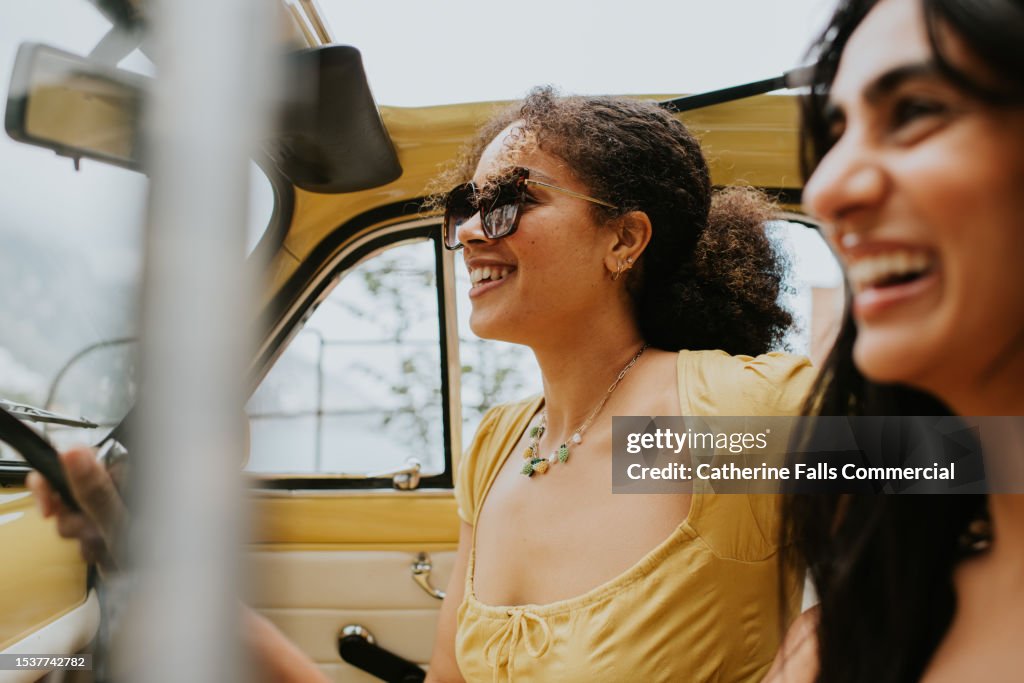 Two woman laughing in a vintage convertible car