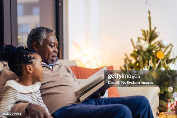 grand mother spending christmas time with her granddaughter - man reading card stock pictures, royalty-free photos & images