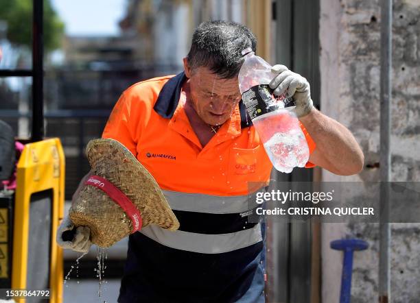 Worker cools off while working in a street during a heatwave in Sevilla, in the southern Spanish region of Andalusia, on July 17, 2023. Scorching...