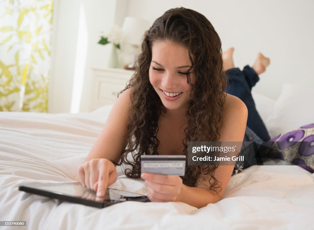 Teenage girl using credit card with digital tablet