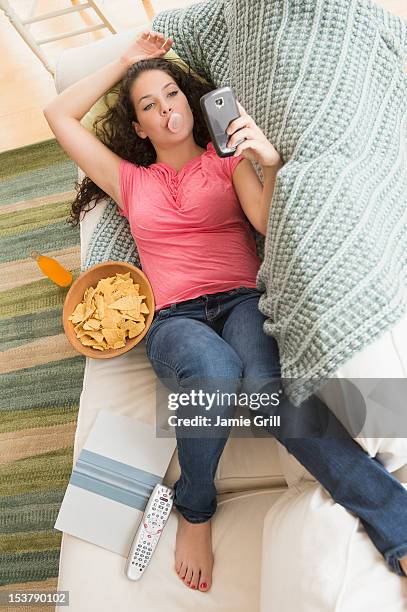 teenage girl on texting on couch with junk food - lying on back girl on the sofa stock pictures, royalty-free photos & images