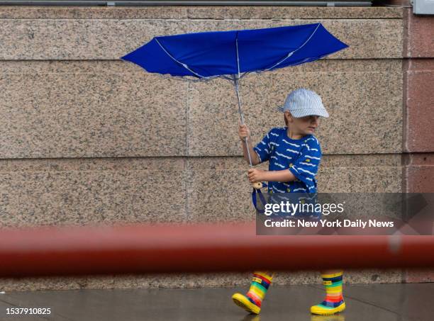 July 16: A young boy fights the strong wind as he and his family walk along the flooded South Street. Major flooding with roadway upheaval was...