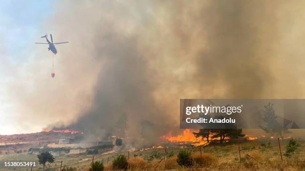 Firefighter helicopter drops water on wildfire as firefighter teams conduct extinguishing works by land and air to control wildfires in Canakkale,...