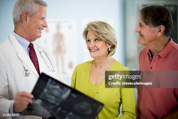 male doctor showing x-ray result to happy couple. - 70 x 54 stock pictures, royalty-free photos & images