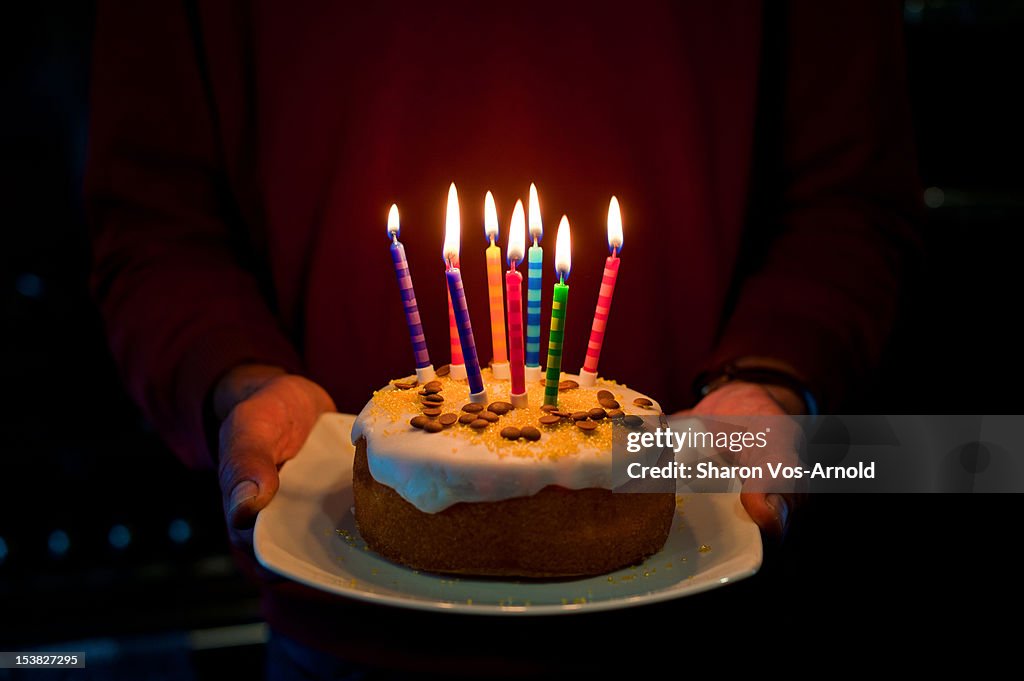Man, birthday cake, 8 glowing coloured candles