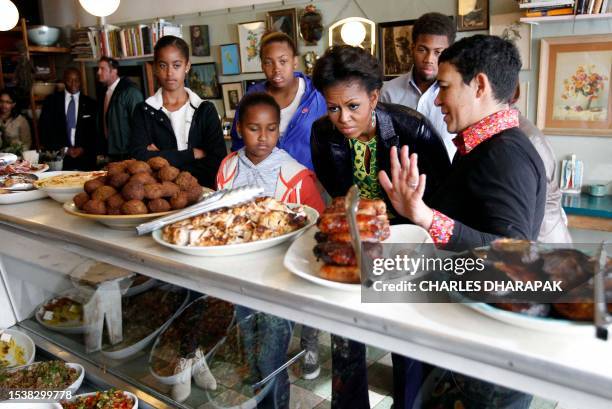 First lady Michelle Obama stands with Karen Dudley , at her restaurant "The Kitchen" as she makes an unscheduled stop for lunch in Cape Town, South...